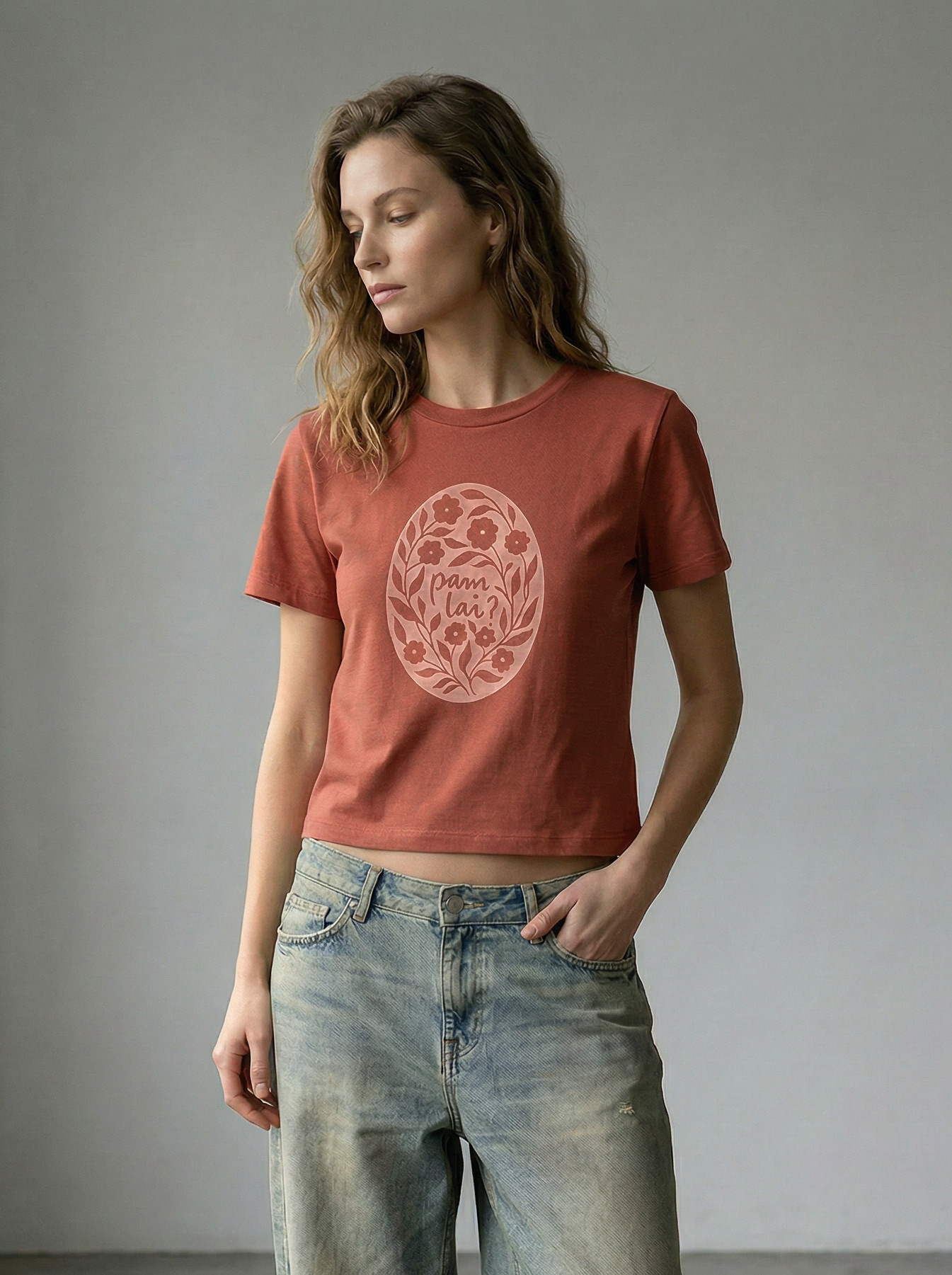 Woman wearing a Welsh t-shirt with a graphic design and blue jeans in a minimalistic setting.