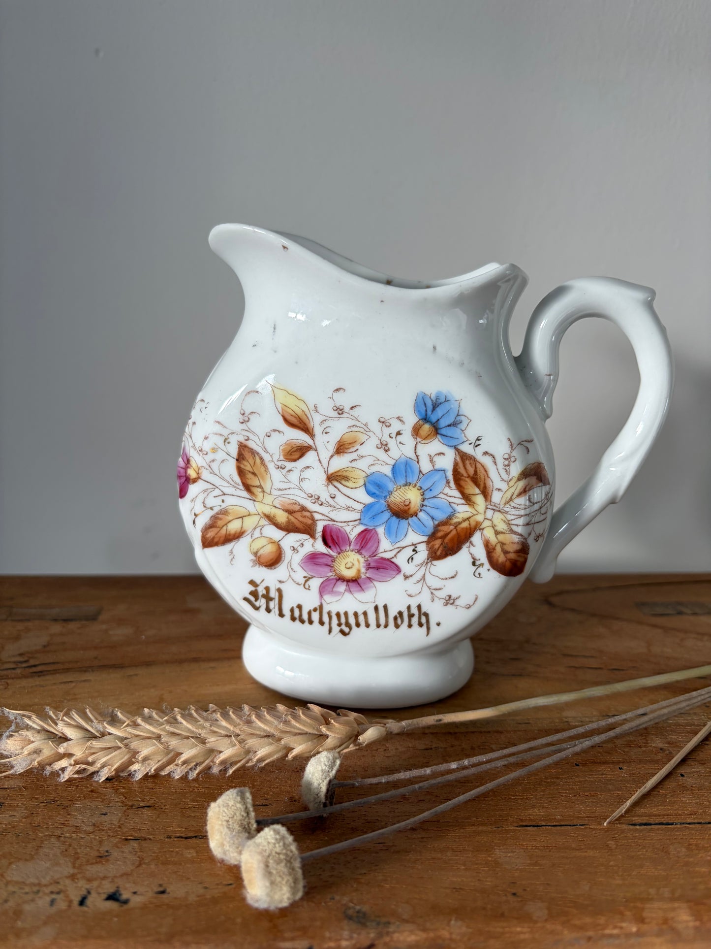 Decorative ceramic jug with floral designs and the word 'Machynlleth' in gold lettering Cymraeg Cymru