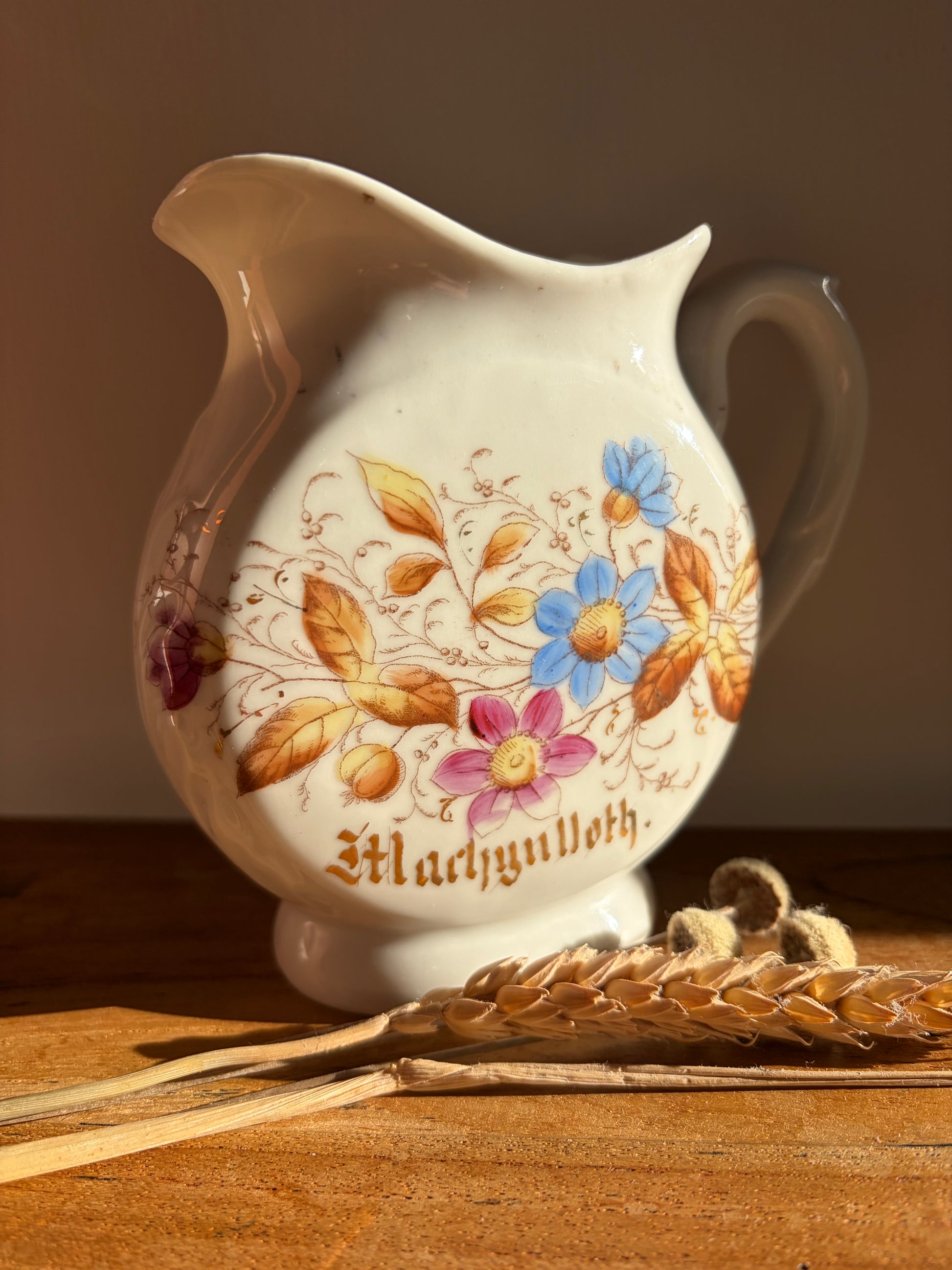 Decorative ceramic jug with floral designs and the word 'Machynlleth' in gold lettering Cymraeg Cymru